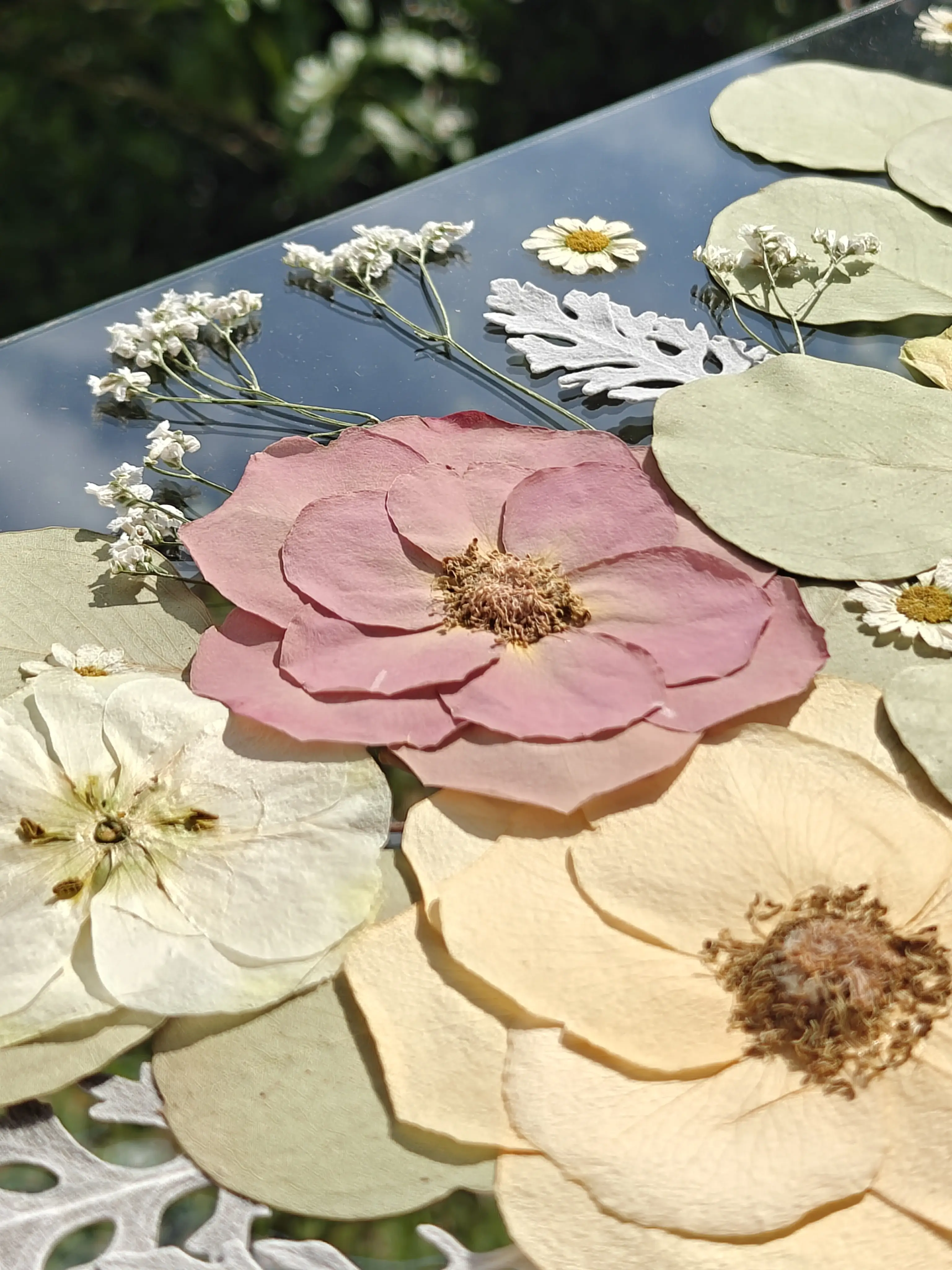 Composição de rosas preservadas em tons de rosa, com margaridas e eucalipto